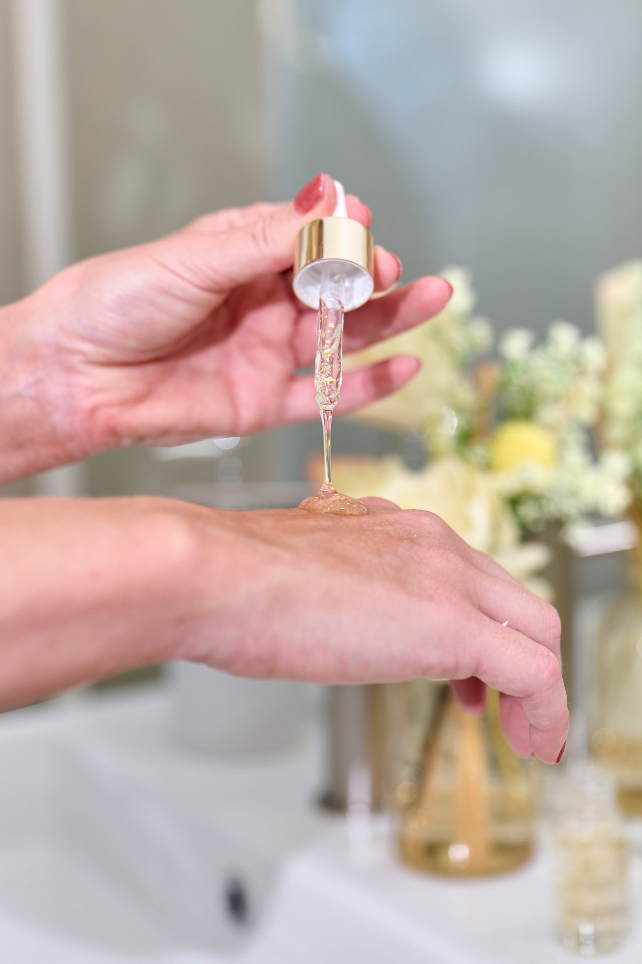 A woman holding a bottle of Suzi Kozmetika serum, dispensing the product onto her hand.